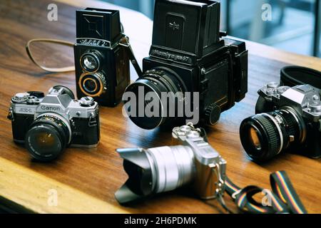 Izmir, Turkey - July 9, 2021: Illustrative editorial shot of Lubitell 2, Mamiya RB67, Fujifilm xt4, Canon AE1 and Fujifilm xA2 Camera on a wooden grou Stock Photo