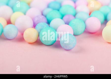 Foam beads of various colors brightly colored on pink pastel background with empty space. Stock Photo