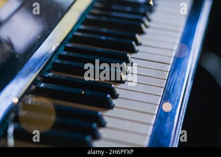 The keys of an old vintage piano in the background light with highlights. Close-up, selective focus Stock Photo
