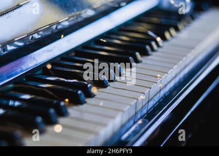 The keys of an old vintage piano in the background light with highlights. Close-up, selective focus Stock Photo