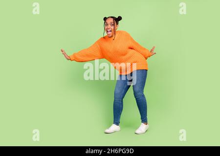 Full length photo of impressed curvy fit young brunette lady dance wear sweater jeans shoes isolated on green background Stock Photo