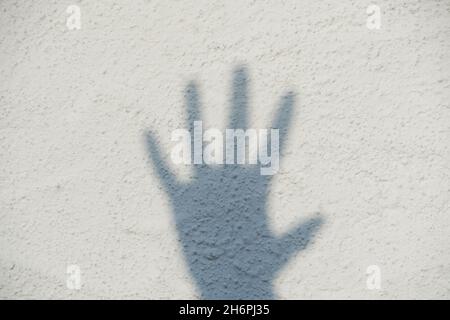Shadow of a hand on a white wall. Five fingers. Stop. Stock Photo