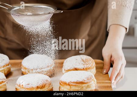 woman-prepares-fresh-donuts-with-jam-in-