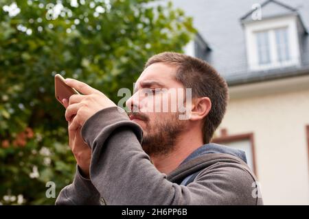 Closeup shot of a young Hispanic man taking a photo of something. Stock Photo