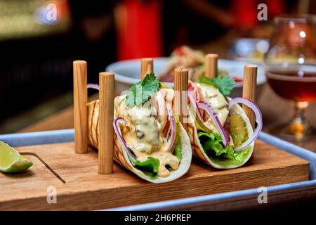 Traditional street mexican pork tacos with beef, tomatoes, avocado, chilli and onions in yellow corn tortilla called Al pastor. Side view of bar count Stock Photo