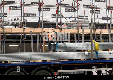 London, England - August 2021: Construction worker wearing safety harness preparing for a load of steel building materials to be lifted by crane Stock Photo