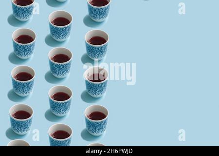 Winter pattern made of tea cups on pastel blue background.  Minimal concept arrangement. Stock Photo
