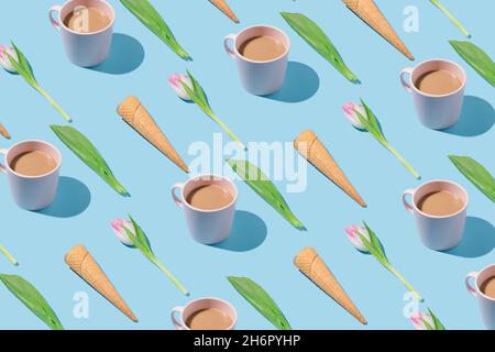 Creative spring pattern made with ice cream cones, pink tulips, coffee cups and green leaves on blue background. Stock Photo