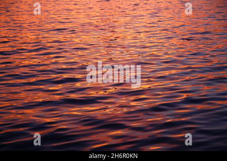 The beauty of the colors of the waves in the water during a summer sunset with a close up shot Stock Photo
