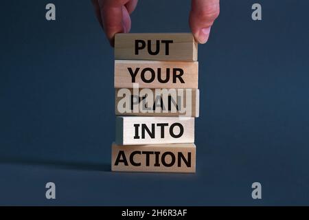 Put your plan into action symbol. Wooden blocks with words Put your plan into action. Businessman hand. Beautiful grey background, copy space. Busines Stock Photo