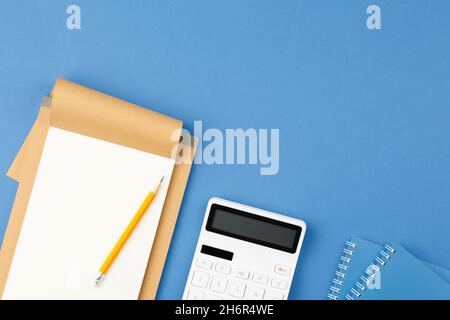 Notepad, pencil and calculator on blue background. Stock Photo