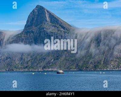 Salmon farm, aquaculture in the Mefjord on Senja island, in the background the peak of famous Segla mountain,  Norway Stock Photo
