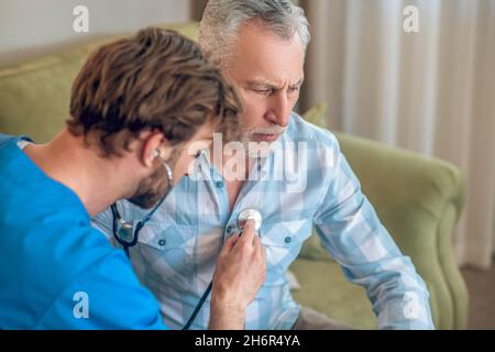 Experienced concentrated physician performing the cardiac auscultation Stock Photo