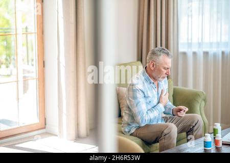 Male having a heart attack on the sofa Stock Photo