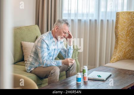 Gray-haired bearded mature man suffering from a headache Stock Photo