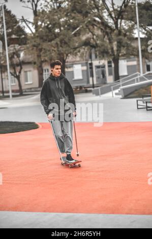 Disabled guy riding skateboard in park Stock Photo