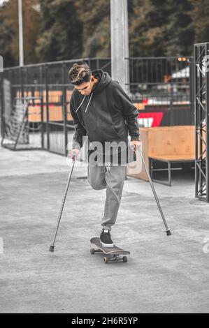 Disabled guy riding skateboard in park Stock Photo