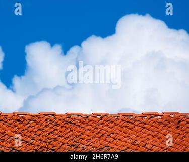 Red roof tiles with white clouds above as background Stock Photo