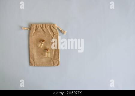 Two empty small glass bottles with stoppers lie on decorative burlap bag on blue background. Top view. Copy space. Copy space for text Stock Photo