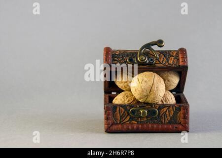 Small chest full of walnuts on gray background. Close-up. Selective focus. Copy space for text. Stock Photo