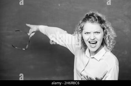 Remember this. Strict woman teacher pointing at chalkboard. Informing kids. School rules. School principal stressful outraged expression. Educational Stock Photo