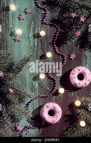 Pink donuts and other Christmas decorations on dark abstract background. Xmas lights , ball garland, pink stars and sparkling heart shape with natural Stock Photo