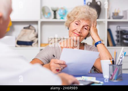 Upset senior woman discussing with husband bills Stock Photo