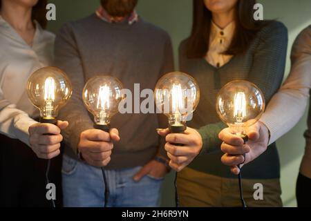 Team of people holding light bulbs to show concept of creative ideas and innovations Stock Photo