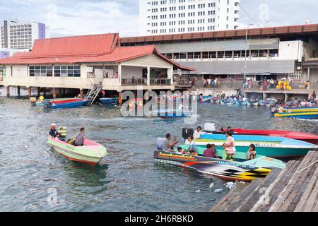Kota Kinabalu, Malaysia - March 23, 2019: Motorboats with passengers are moored near KK Fish Market on a sunny day, cheap public transportation betwee Stock Photo