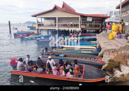 Kota Kinabalu, Malaysia - March 23, 2019: Motorboats full of passengers are moored behind KK Fish Market on a sunny day, cheap public transport betwee Stock Photo