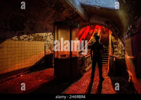 Urban explorer in dark and creepy old abandoned subway station. Stock Photo