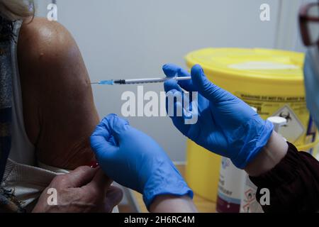 London, UK. 15th Nov, 2021. A NHS health worker administers the Pfizer/BioNTech Covid-19 booster jab to a woman at a vaccination centre as the NHS is preparing for a possible annual Covid-19 booster jabs programme. Credit: SOPA Images Limited/Alamy Live News Stock Photo