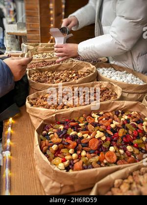 Closeup female hand giving money for dried fruits and nuts at market in Ukraine Stock Photo