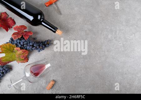 Red wine bottle with bunch of grape, fall grape's leaves on gray background, top view Stock Photo