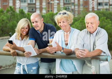 Family of four using gadget in park outdoor Stock Photo