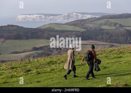 A couple walking across Mottistone Downs overlooking the chalk cliff faces on the coast of the Isle of Wight, South England, United Kingdom Stock Photo