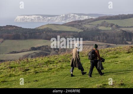 A couple walking across Mottistone Downs overlooking the chalk cliff faces on the coast of the Isle of Wight, South England, United Kingdom Stock Photo