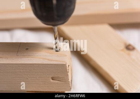 Drill bit makes a hole for screw in wooden plank. Close up, selective focus, and copy space Stock Photo