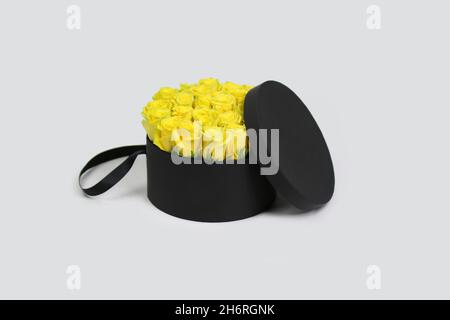 Black round gift flower packaging box with yellow roses inside and opened lid. Stylish flower arrangement. Stock Photo