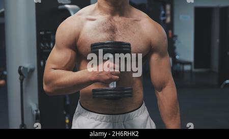 Muscular arab man training with dumbbells in the gym. Stock Photo