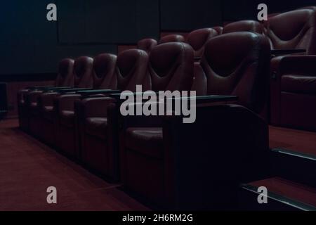 rows of brown leather armchairs in an empty cinema hall in a movie theater during coronavirus quarantine. Stock Photo