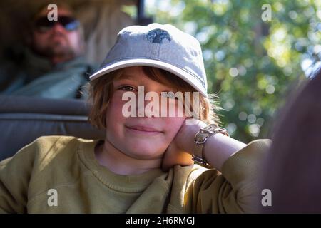 A boy sitting in a jeep leaning on his elbow in a safari jeep. Stock Photo