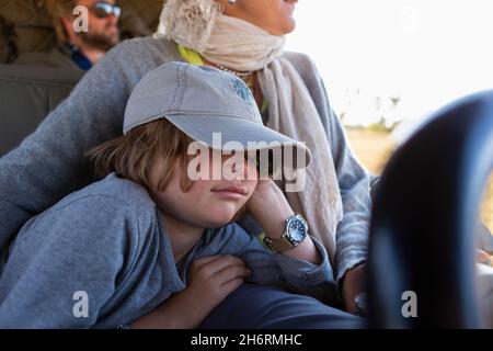 Eight year old boy in safari vehicle, sleeping beside his mother, in a safari jeep Stock Photo
