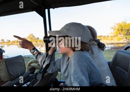 Boy in a safari jeep looking through binoculars. Stock Photo
