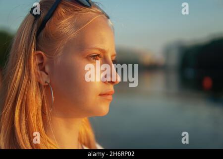 blonde teen girl standing on the lake at sunset. Stock Photo