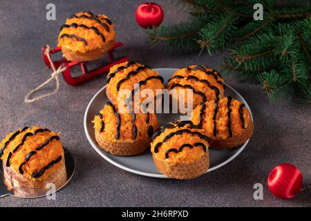 Tiger canapes for New Year 2022 of salted herring, carrot and black olives on croutons of white bread on brown background. Close-up Stock Photo