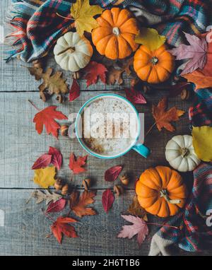 Overhead of pumpkin spice latte on wood with leaves and pumpkins. Stock Photo