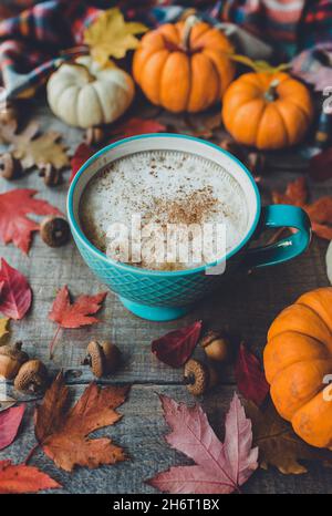 Pumpkin spice latte on wooden table with leaves and pumpkins. Stock Photo