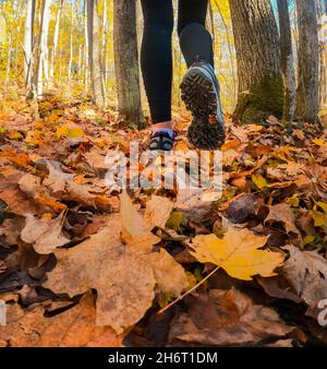 Cropped close up of a woman's legs on a leafy hiking trail. Stock Photo