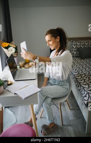 Woman sitting at her working desk and taking a selfie. Stock Photo